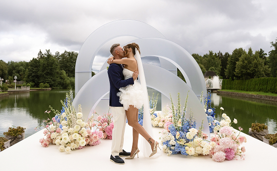 Поцелуй молодоженов на фоне свадебного декора и водоемов